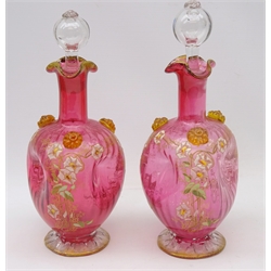  Pair Victorian cranberry tinted glass decanters, pinched waisted form, enamelled with Art Nouveau style trailing flowers & foliage, applied clear glass flower heads, clear glass stopper & gilded highlights, H29cm   