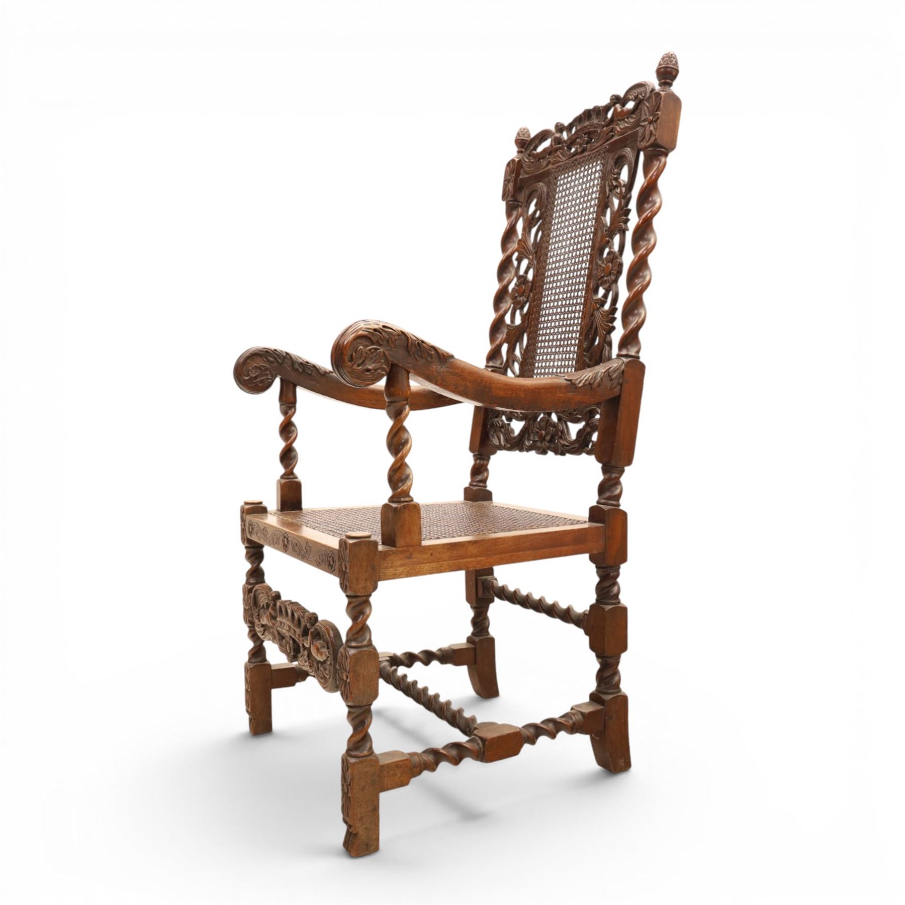 Late Victorian Jacobean Revival oak armchair, the caned back within a pierced and carved foliate frame surmounted by acorn finials, carved scroll arm supports, caned seat, on barley twist supports united by stretchers and carved front rail