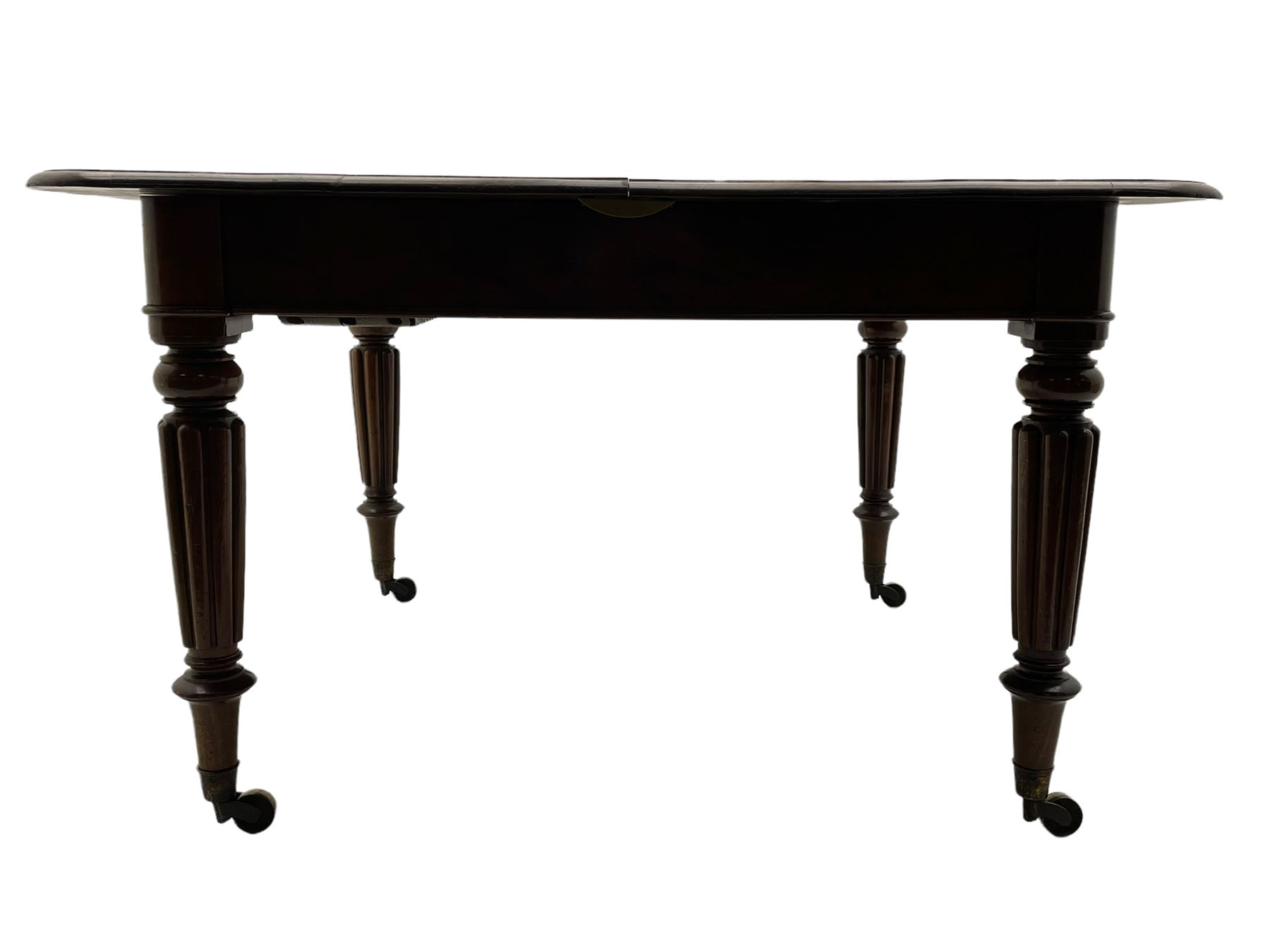 Early 19th century figured mahogany extending dining table, the rectangular top with moulded edge and rounded corners, pull-out action with three additional leaves, raised on turned and lobe carved supports with brass cup castors