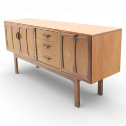 G-Plan - ‘Brasilia’ teak sideboard, rectangular top with moulded edge above a central bank of four drawers flanked by cupboard doors with carved sculptural handles, raised on tapering supports
