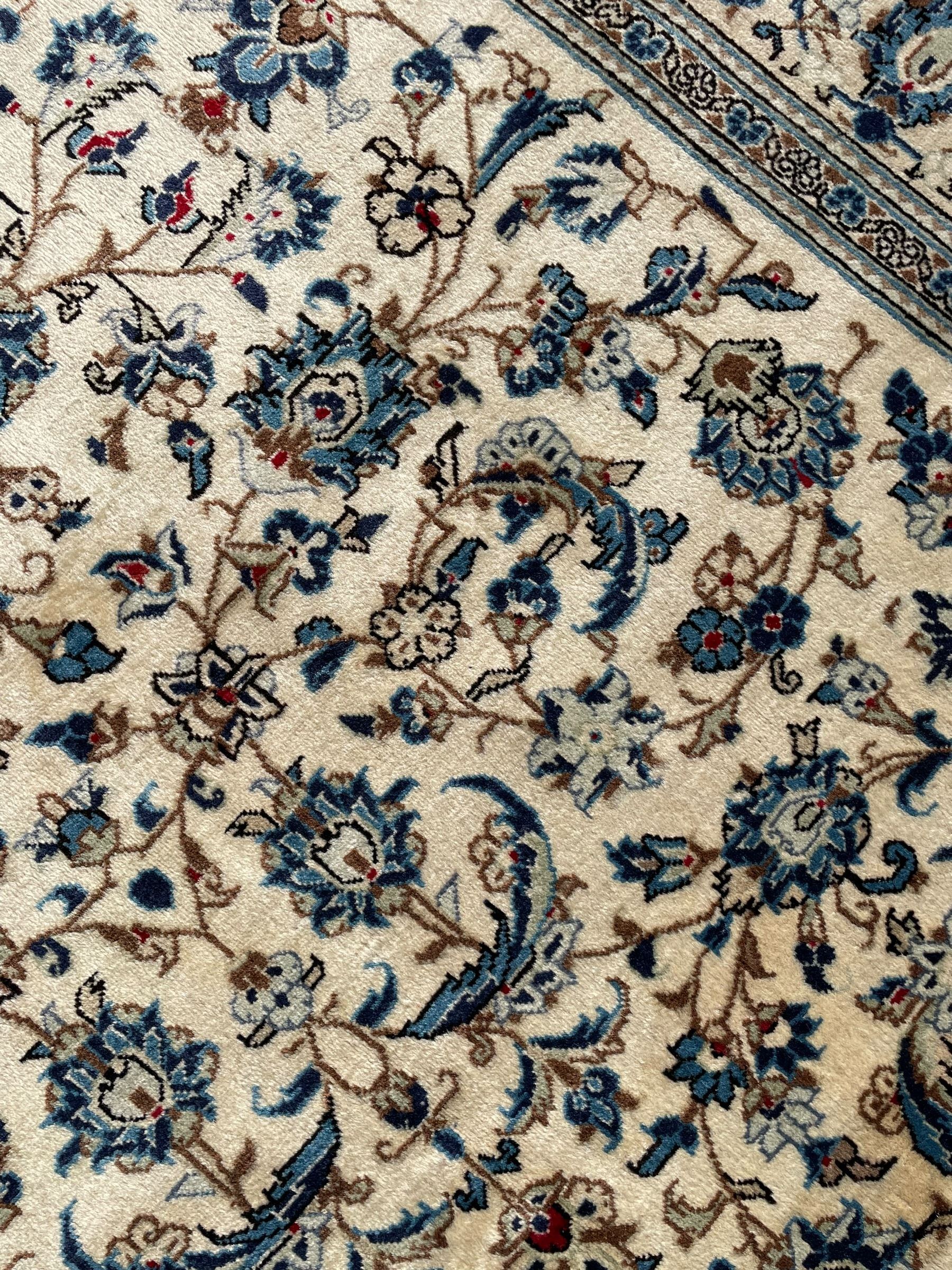Persian Kashan ivory ground rug, the field decorated with trailing branches with leaves and palmettes, similar scrolling border, within floral pattern guard stripes 