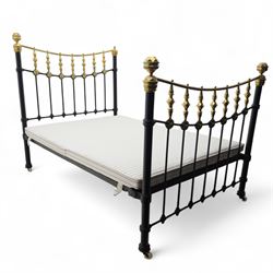 Victorian brass and iron 4' 6'' double bedstead, curved brass top rail with cast iron spindles and ornate floral rosettes flanked by urn shaped finials, foldable divan style base upholstered in a striped fabric, supported on turned posts and ceramic castors