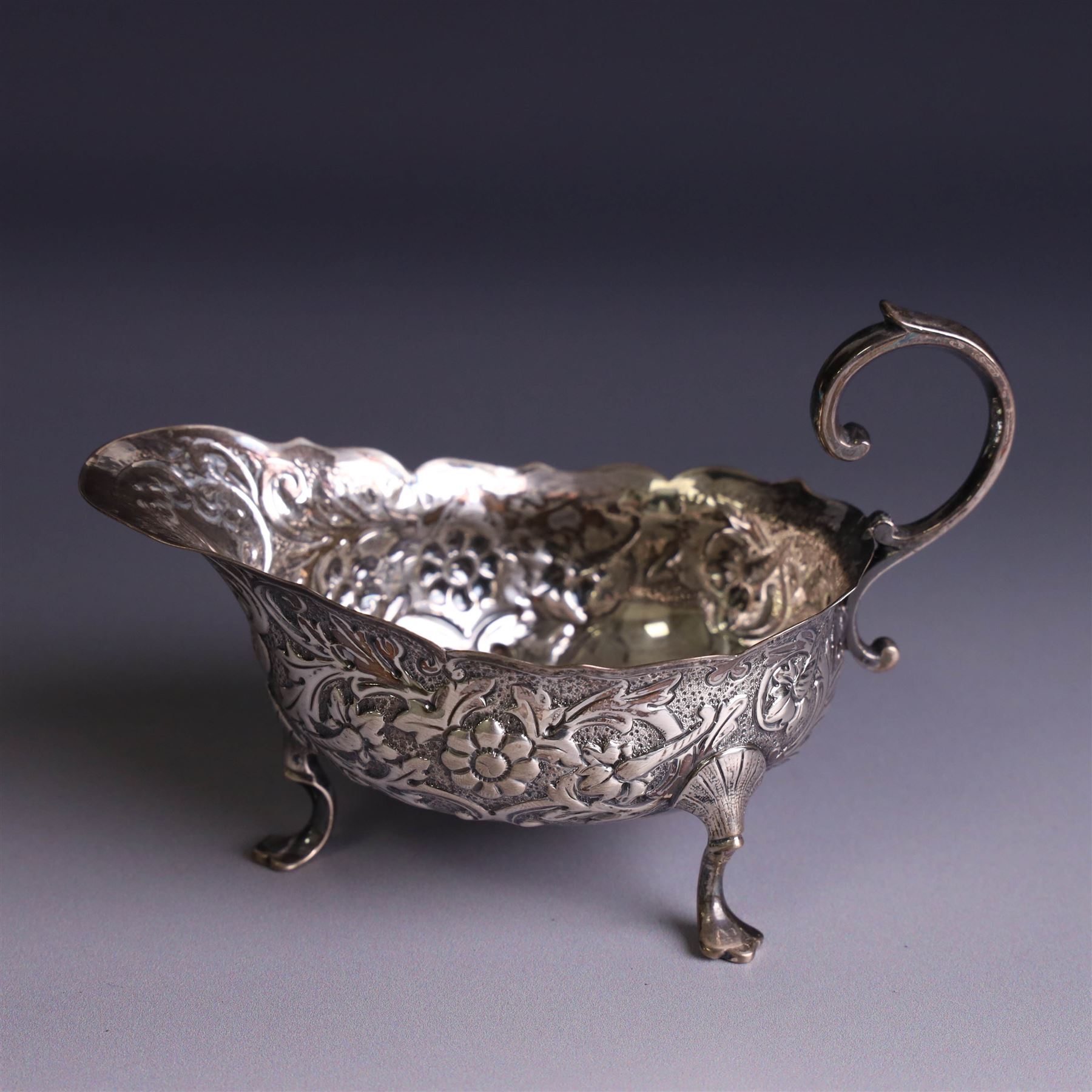Victorian silver sauceboat, of typical form with embossed floral and foliate decoration, hallmarked London 1886, together with a miniature silver trophy and silver pickle fork, both hallmarked, trophy H7.5cm
