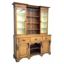 Late Victorian oak dresser, reverse break front top with projecting cornice, three central shelves flanked by glazed display cabinets, the base fitted with three drawers, two cupboards and shelves