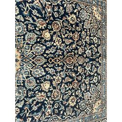 Persian Kashan indigo ground rug, the rosette medallion decorated with projecting palmettes, on a field of swirling leafy branches and decorated with further palmettes, the scrolling border with repeating stylised plant motifs, within floral pattern guard stripes
