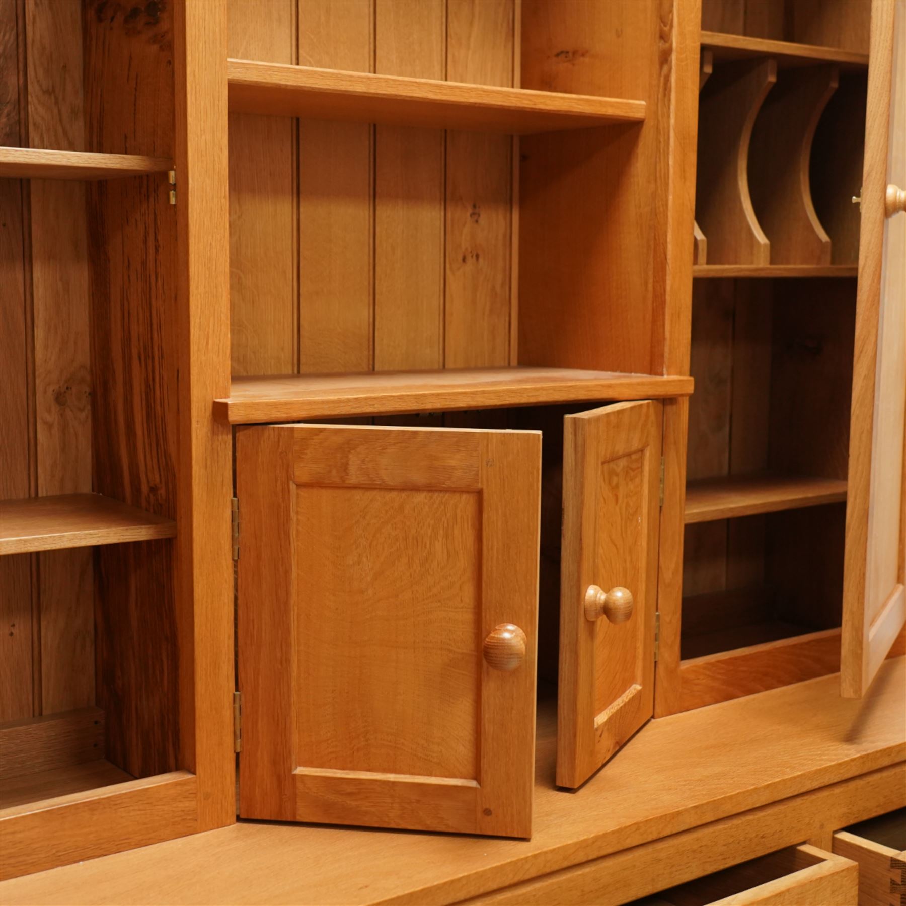 Yorkshire oak dresser, projecting top over open centre fitted with shelf, small double cupboard and flanking full height cupboards, the lower section fitted with three drawers and cupboards, enclosed by panelled doors, on plinth base