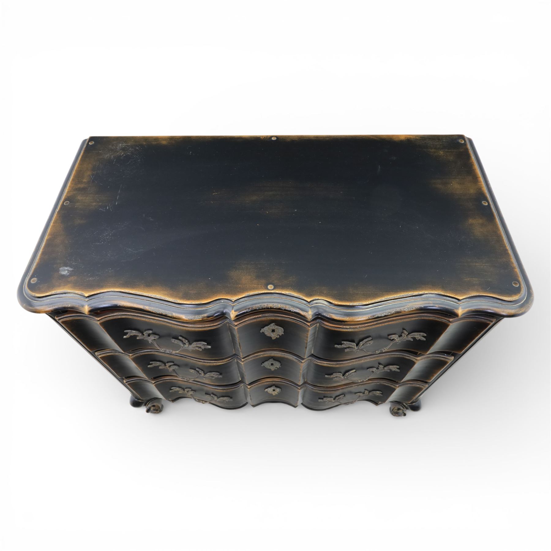 French style black lacquered chest of drawers, the serpentine front fitted with three graduated drawers mounted with scrolling foliate metal handles and key plates, shaped apron and scrolled cabriole legs