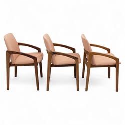 Mid-20th century Danish teak armchairs, each with curved open arms and upholstered seat and backrest in salmon pink striped fabric, raised on tapering legs