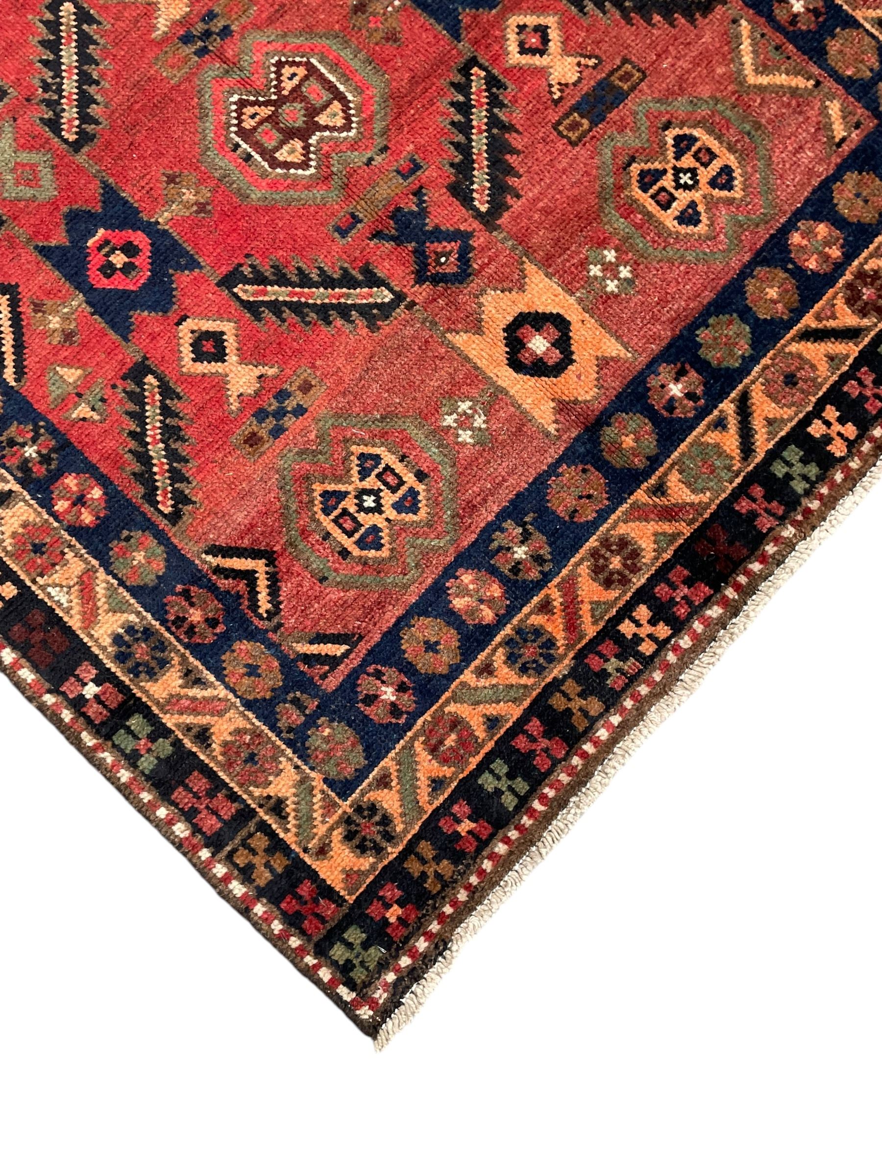 Near pair of Persian Azerbaijan red ground runners, each rug decorated with Nazarlik and stylised leaf motifs, enclosed with three band border decorated with flower heads and geometric motifs 

406cm x 99cm 
409cm x 102cm
