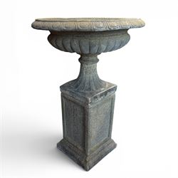 Pair of cast stone garden urns of kylix form on pedestals, the broad egg-and-dart moulded rim over a shallow gadrooned underbelly, with waisted tapering base, raised on matching plinth bases with faux panelled facia