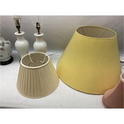 Three white ceramic table lamps, one decorating with fruiting branches, all on turned wood bases, together with a quantity of fabric shades largest H35cm excl fitting