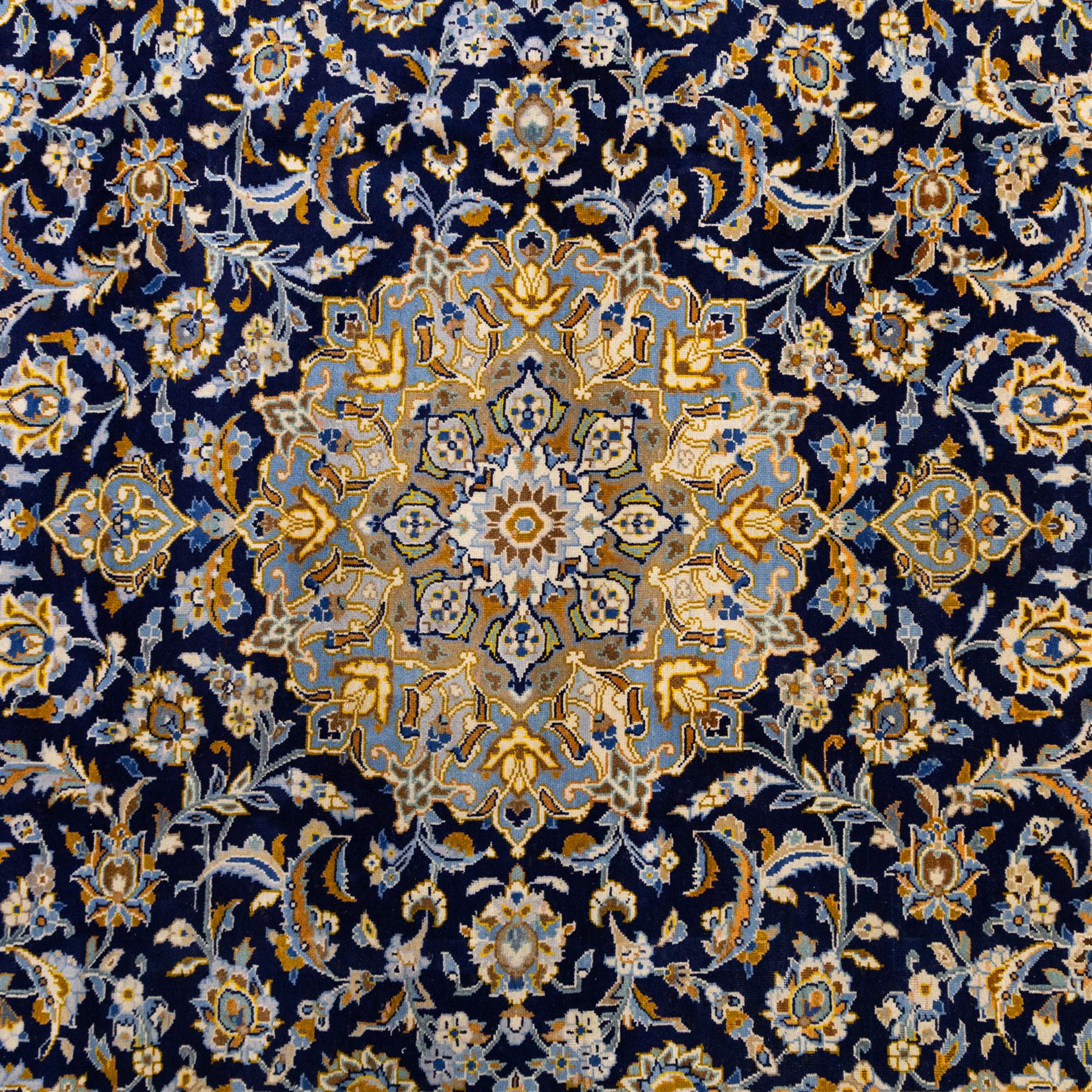 Central Persian Kashan hand-knotted rug, deep indigo field with central floral medallion surrounded by an all-over arrangement of palmettes, flowering vines, and tendrils with matching spandrels enclosed by a pale blue floral main border with multiple narrow guard stripes, with cotton fringe ends 