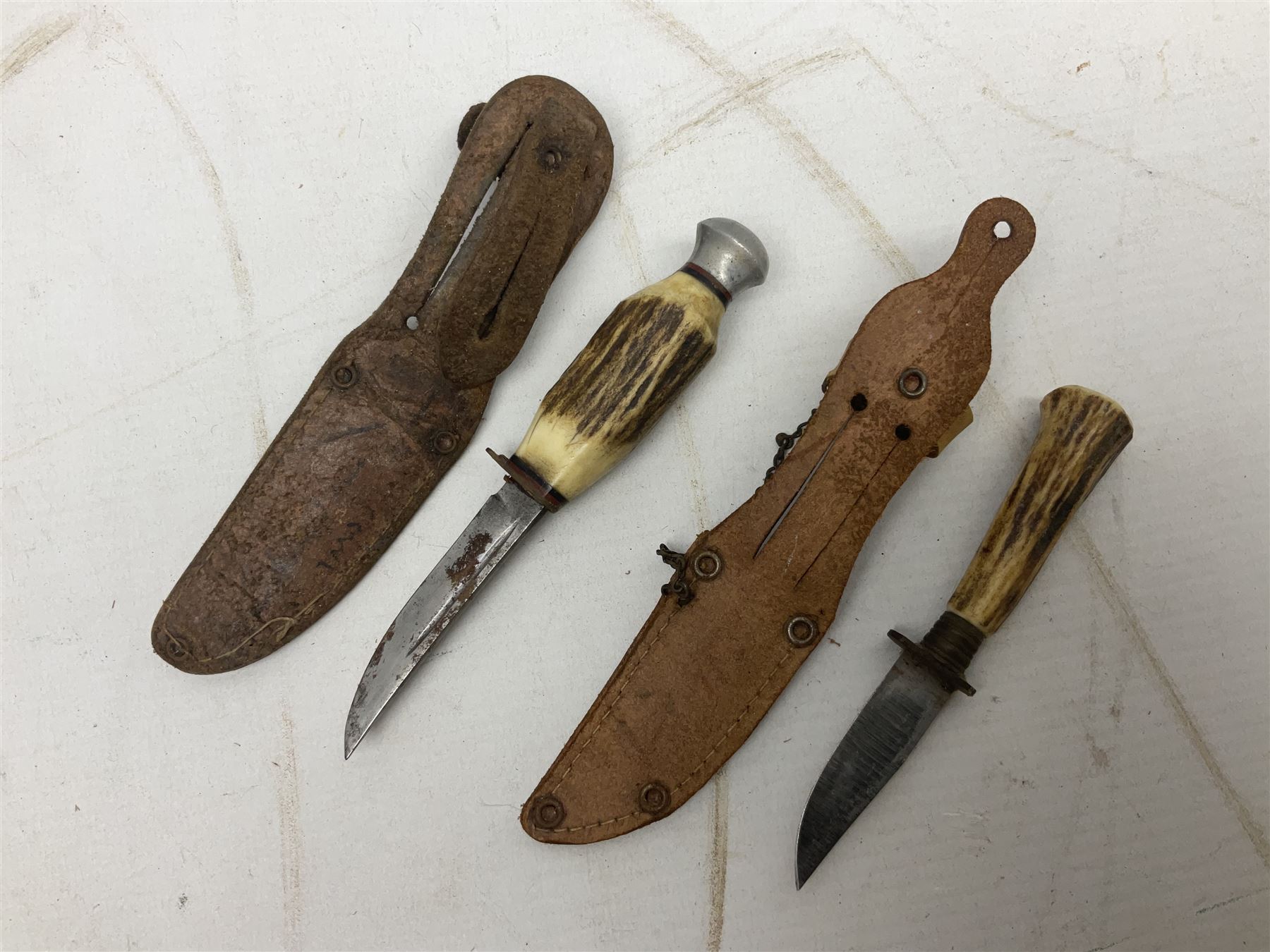 Eastern dagger with 14.5cm ornate fullered blade and nickel mounted horn grip; in nickel mounted ebonised wooden scabbard L25,5cm overall; another smaller Eastern dagger with animal head pommel and nickel mounted leather scabbard; three small sheathe knives with simulated antler grips; letter opener in the form of a German hunting knife with hoof grip; and Japanese wooden Floating Fish Knife with stainless steel blade (7)