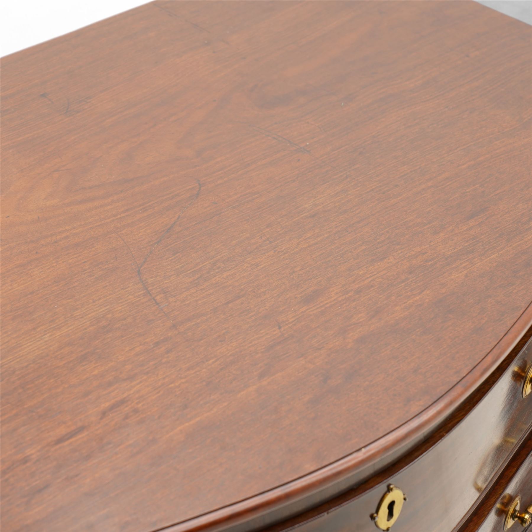 George III mahogany serpentine chest, moulded top over four cock-beaded drawers, the top drawer fitted with baize lined slide opening to reveal divisions,  enclosed by canted and fluted upright corners, the drawer fronts fitted with brass swan neck handles and circular plates with oval escutcheons, lower moulded edge over bracket feet, on lignum vitae castors