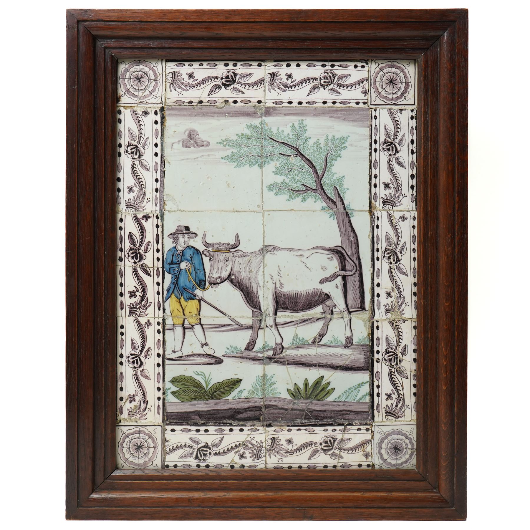 Late 18th/ early 19th century Dutch delftware tile picture of a rural scene with a farmer leading a cow within a floral surround, framed 62cm x 49cm overall