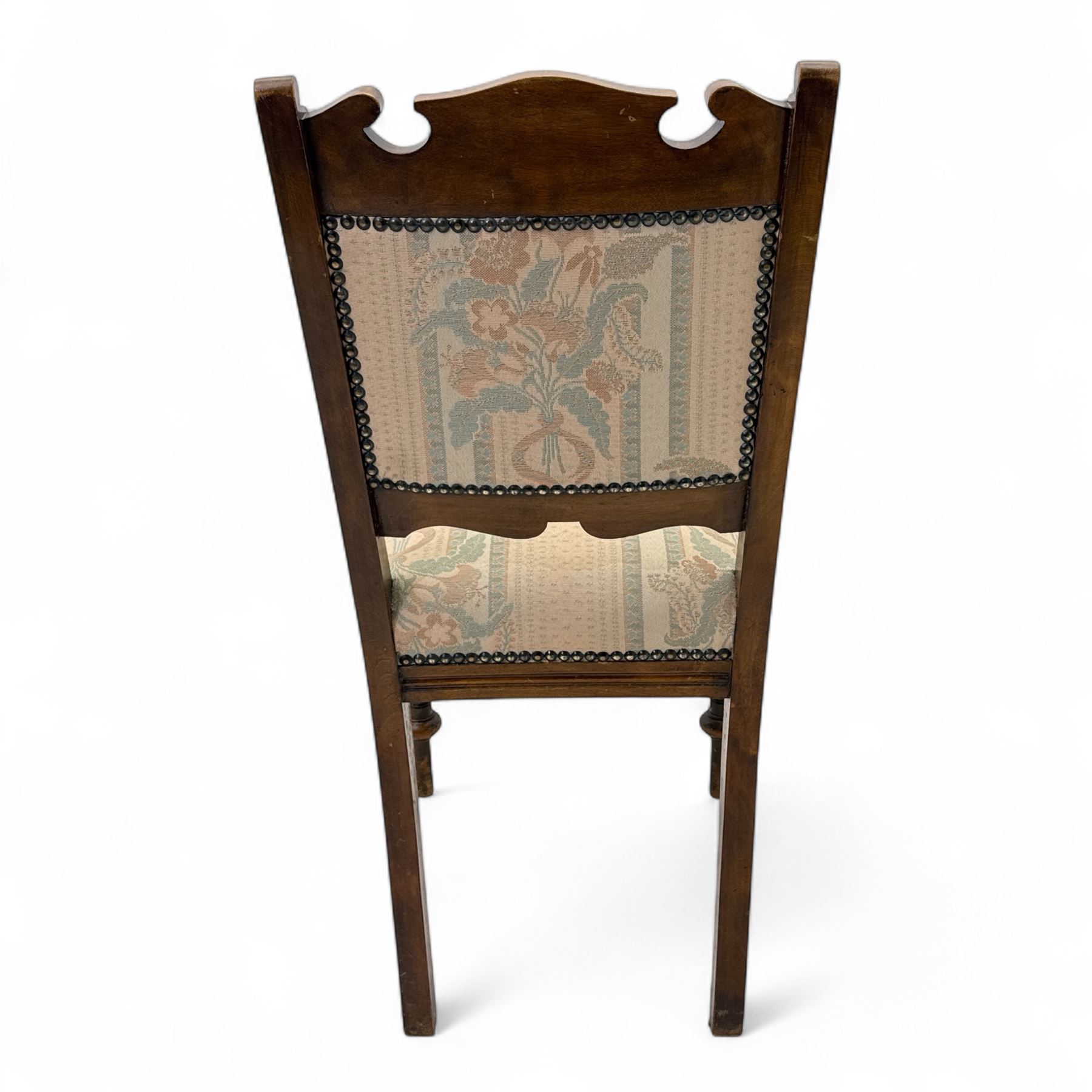 Victorian walnut set of four dining chairs, the shaped and carved top rails with central flowerhead and scroll decoration above upholstered backs and seats in floral woven fabric, brass stud trim, on ring turned front supports
