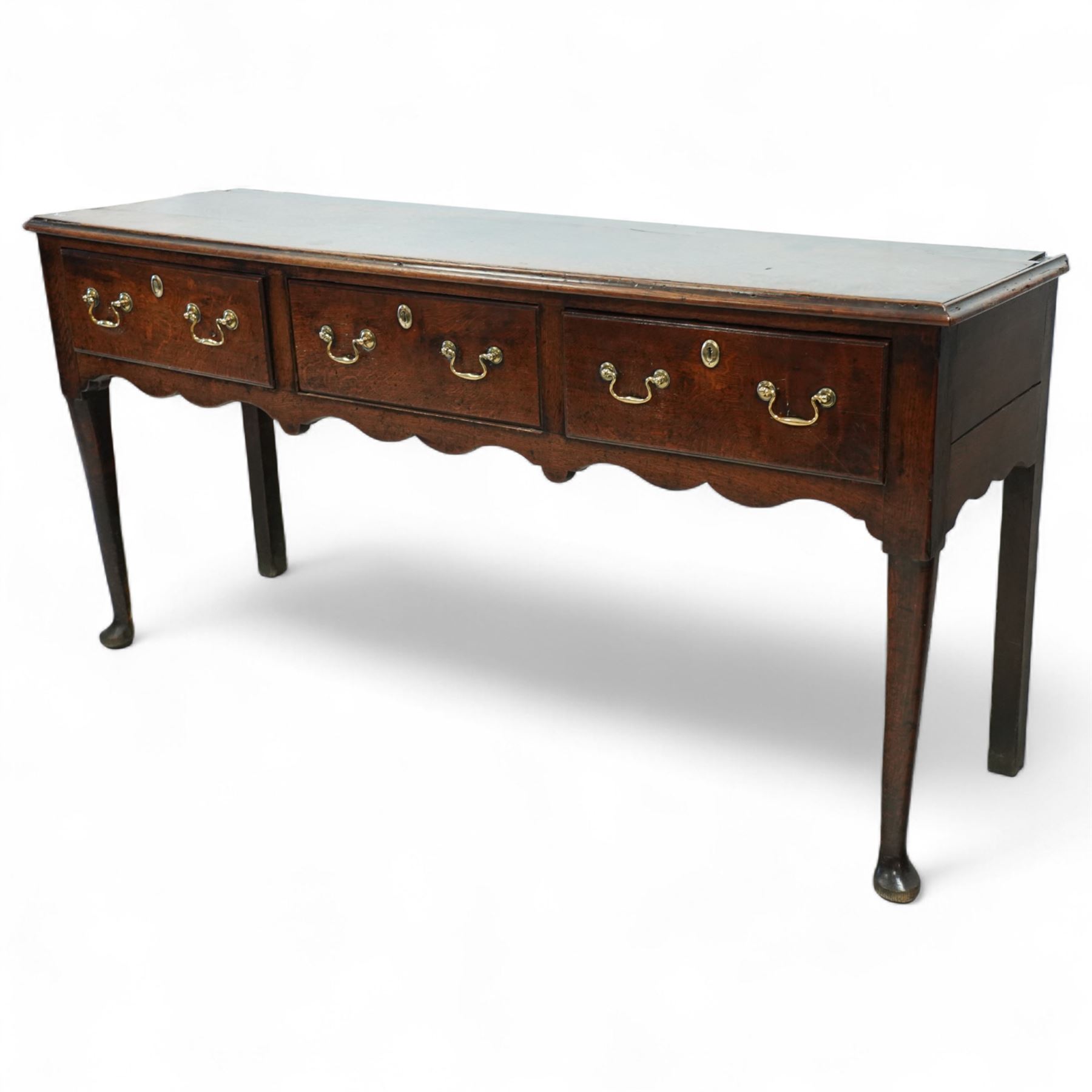 George III oak dresser base, fitted with three drawers with brass swan-neck handles, shaped apron and cabriole legs on pad feet 