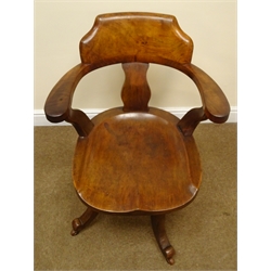  Edwardian walnut swivel office chair, curved shaped back and arms with saddle seat the four scrolled supports with ceramic castors   