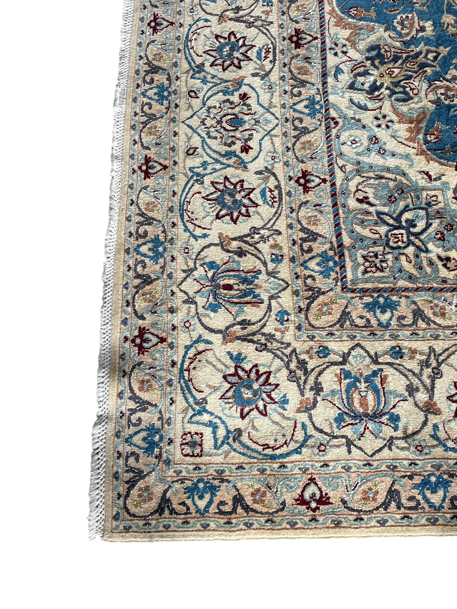 Persian Nain blue and ivory ground rug, wool with silk inlay, overall arabesque design, central medallion surrounded by interlacing and scrolled leafy branches and palmettes, the scrolling border decorated with stylised plant motifs, within guard stripes