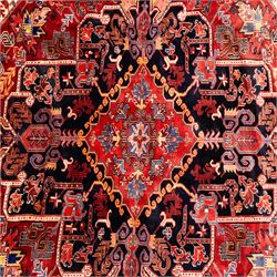 North West Persian Heriz hand-knotted carpet, madder red field with large central stepped medallion with angular floral and geometric designs, surrounded by stylized palmettes, leaves and tribal motifs with indigo corner spandrels, enclosed by a broad navy border of geometric floral devices between multiple guard stripes, with cotton fringe ends 