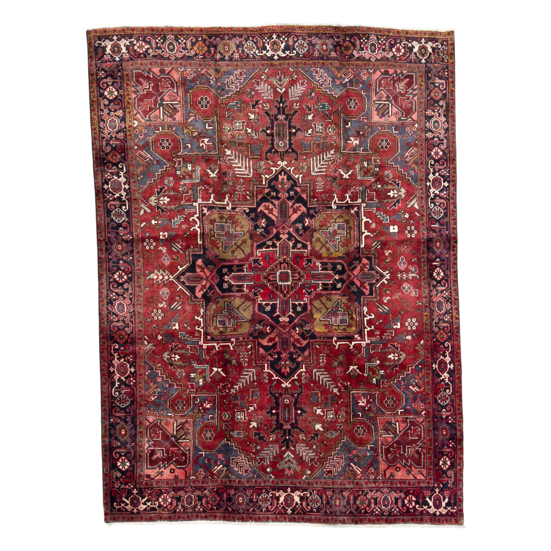 Northwestern Persian Heriz hand-knotted carpet, madder red field with a bold stepped medallion in indigo, ivory, and ivory, surrounded by angular floral motifs and stylized leaves, and the spandrels set within a dark border of rosettes and angular vine motifs, 335cmx252cm