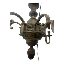 Pair of mid-20th century brass chandeliers, each with cast foliate and scroll decorated central body, issuing six scrolling arms with circular drip pans and bulb holders, suspended from integral ceiling loops