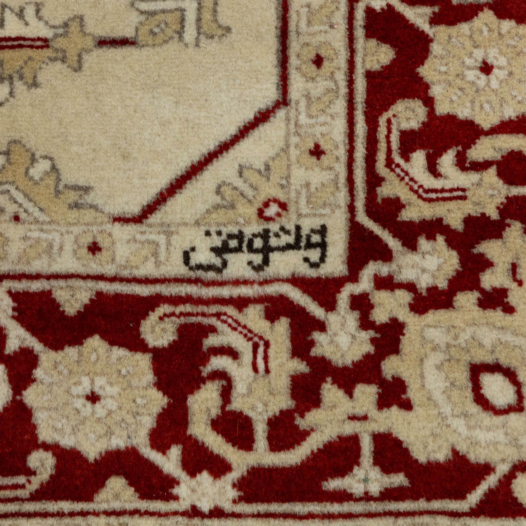 Baluchi signed hand-knotted rug, ivory ground, with an all-over geometric lattice design incorporating stylised flowerheads, hooked motifs and angular vine work, enclosed by a crimson border with repeating floral motifs and scrolling vines, flanked by narrow patterned guard stripes, signed to one corner, with cotton fringes