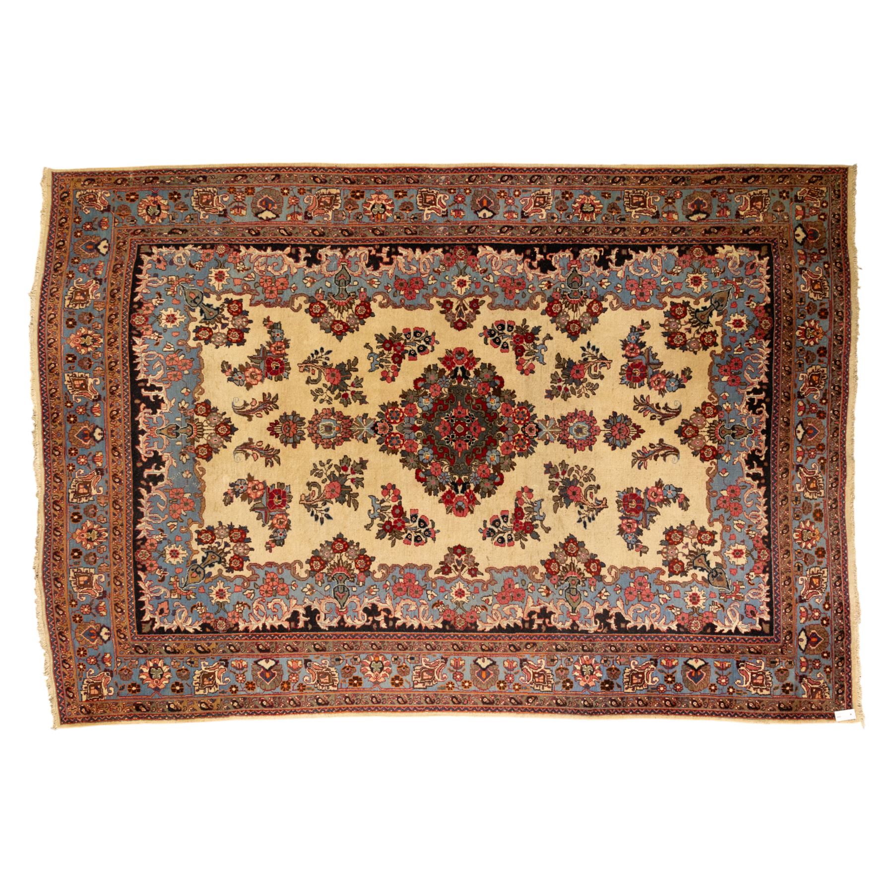 Central Persian Kashan hand-knotted carpet, cream ground, with a central lobbed floral burgundy, rose, and indigo medallion, surrounded by scrolling sprays of carnations and palmettes, with sky blue spandrels decorated with curvilinear vines and stylized blossoms, framed by a repeating terracotta border of palmettes, framed by narrow guard stripes 