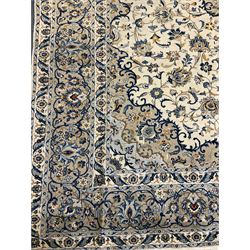 Large Persian Kashan carpet, ivory ground with blue tone pattern, the field decorated with interlacing branches and plant motifs, repeating scrolling border with guards