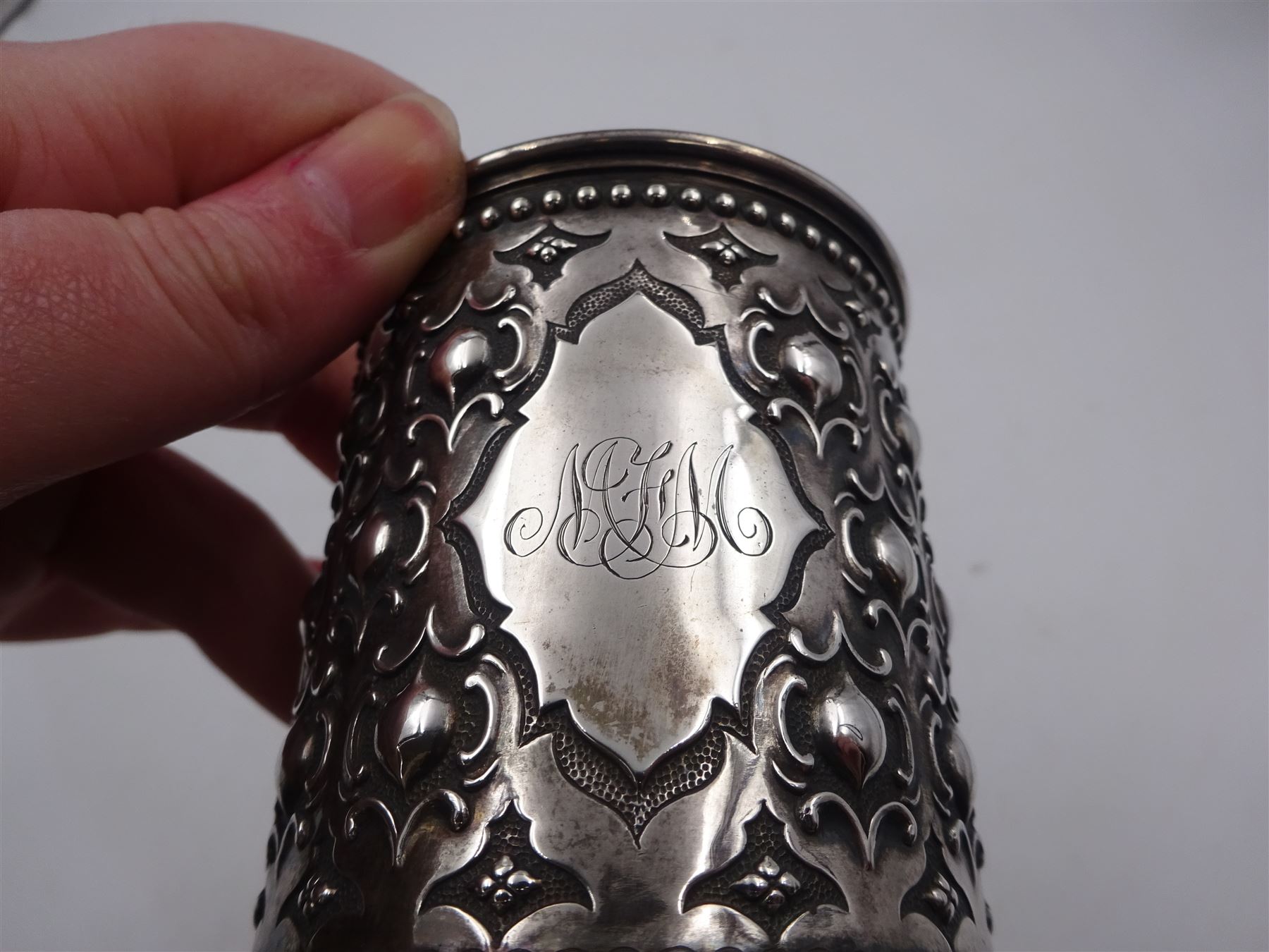 Victorian silver christening mug, with repousse and chased scroll and bead decoration, lozenge shaped cartouche engraved with monogrammed initials and acanthus capped C scroll handle, hallmarked Robert Hennell III, London 1861, H9.3cm