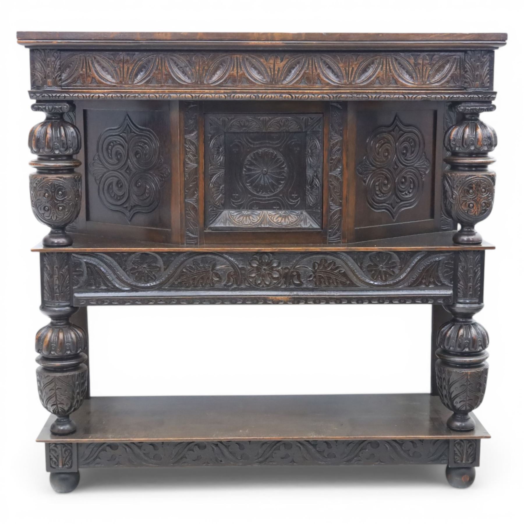 Jacobean revival oak side cabinet, rectangular top above carved frieze of stylised foliage and lunettes, fitted with a central cupboard doors with applied carved panels, above a frieze drawer, supported on turned and carved vase-shaped supports, united by stretcher tier and lower shelf