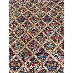 Persian Kirman indigo ground carpet, the field with repeating lozenge tiles with overall floral decoration, the main border with floral panels enclosed by the guards