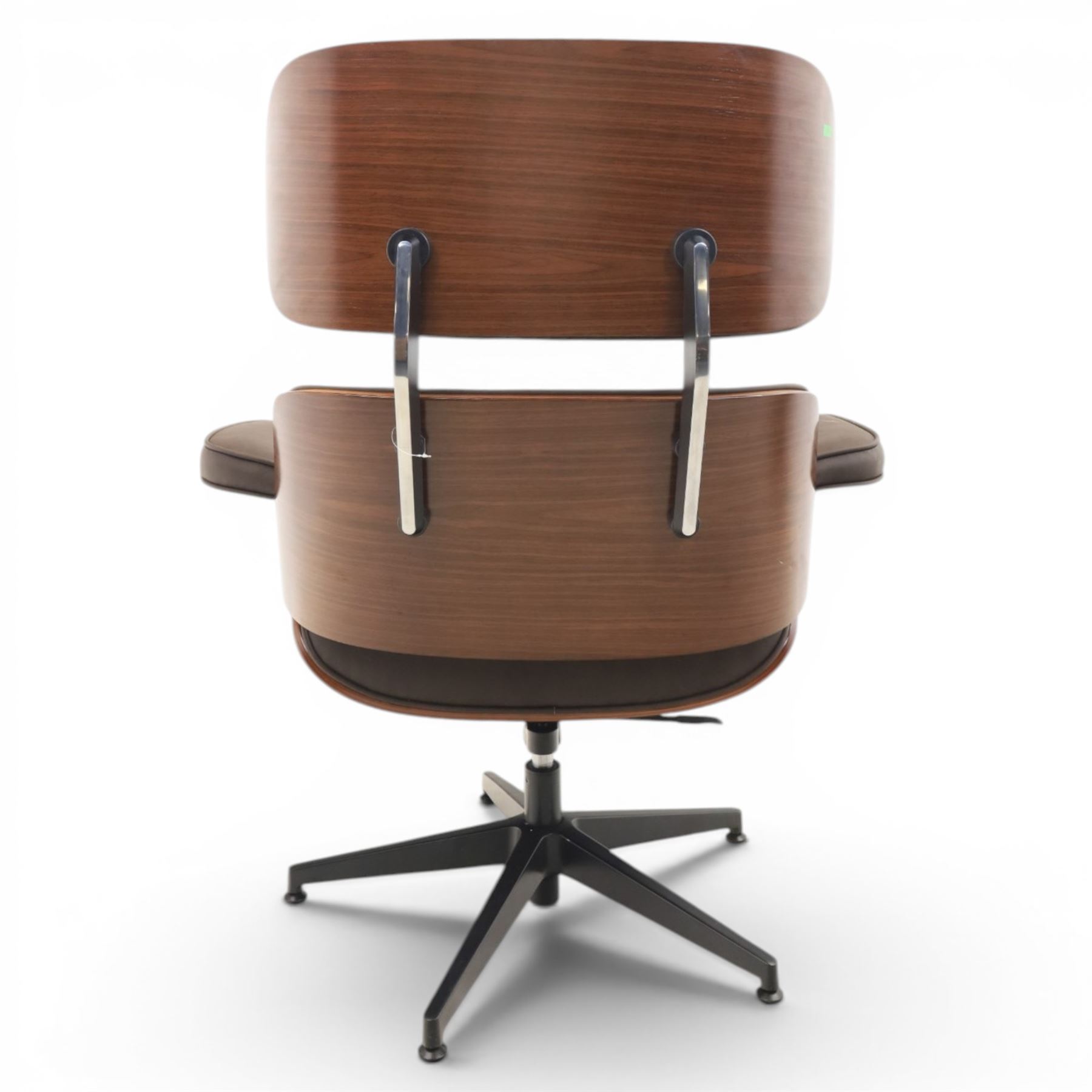 In the manner of Eames' Lounge chair, contemporary brown leather and plywood recliner and footstool, padded leather seat and arm rests, plywood backs raised on a black metal frames, reclines and swivels on a five point base  