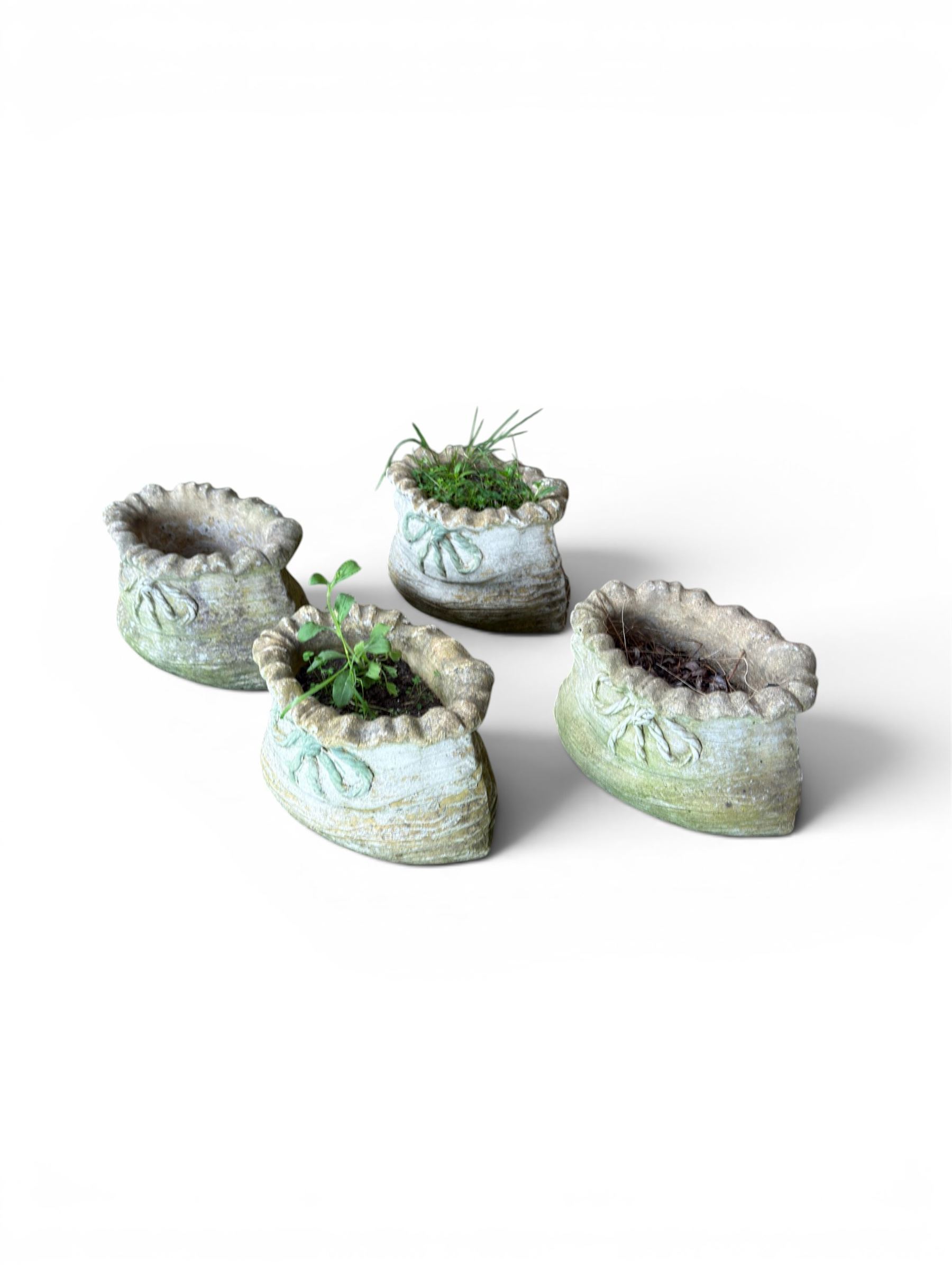 Four cast stone garden planters in the form of ribbon tied planting sacks