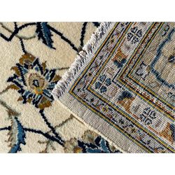 Persian Kashan ivory ground carpet, overall floral design, the field decorated with scrolling and interlaced leafy branches interspersed with palmettes, scrolling border decorated with stylised plant motifs, within floral pattern guard stripes 