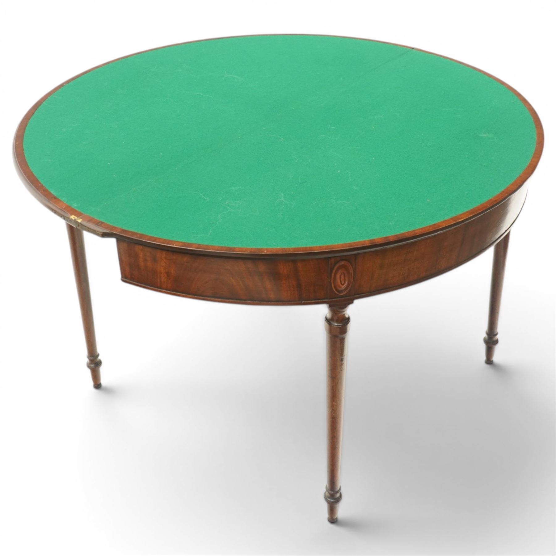 Georgian mahogany demi-lune card table, the lunette shaped top with cross-banded and boxwood-strung edge, opening to reveal baize-lined interior and supported by rear gatelegs, over a banded frieze with applied oval plaques, raised on turned and tapering supports
