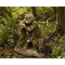 Carved composite stone garden figure, depicting a seated child with folded arms, weathered...