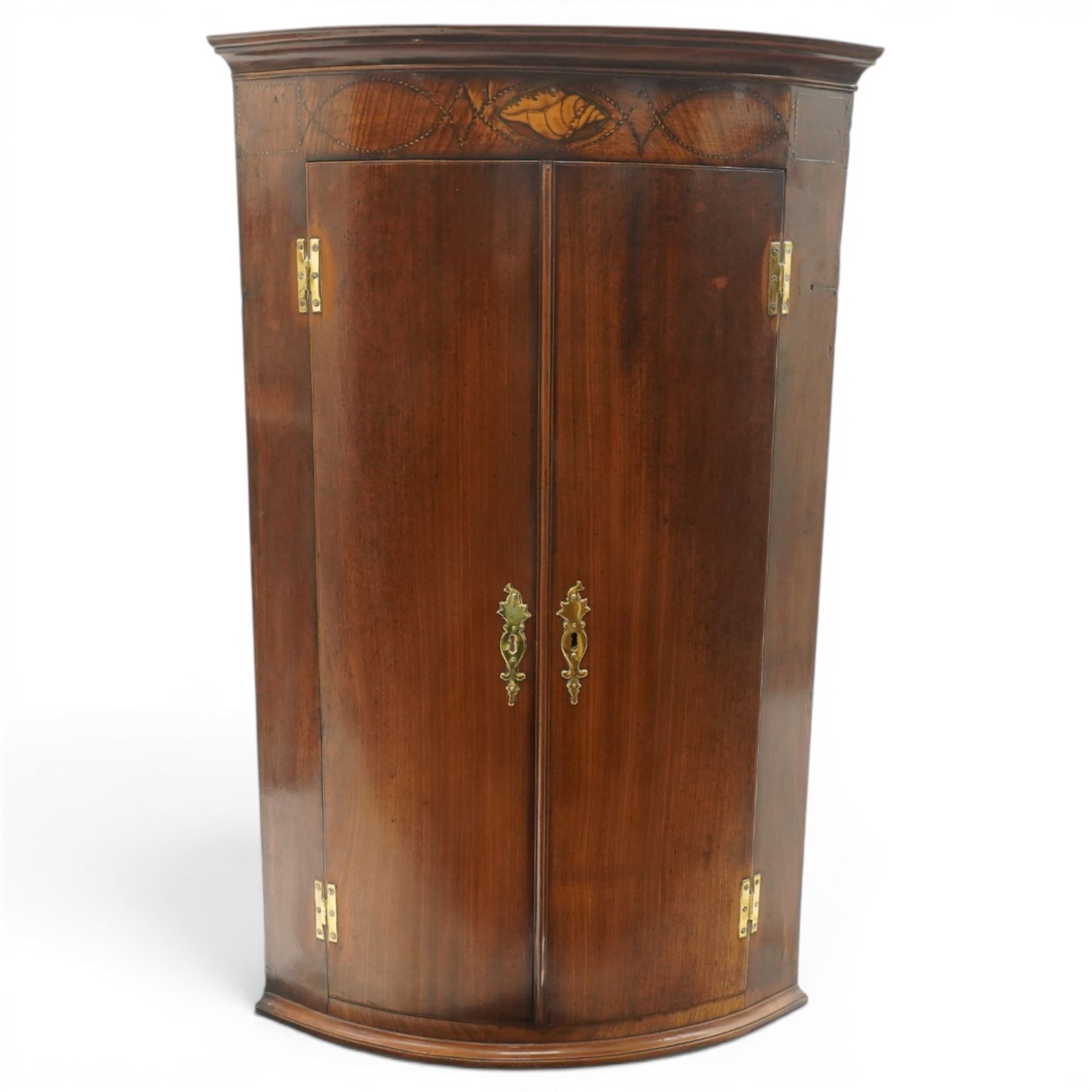 Georgian inlaid walnut cylindrical corner cupboard, projecting cornice over a banded frieze with inlaid shell motif, enclosing three shelves with two spice drawers fitted to base