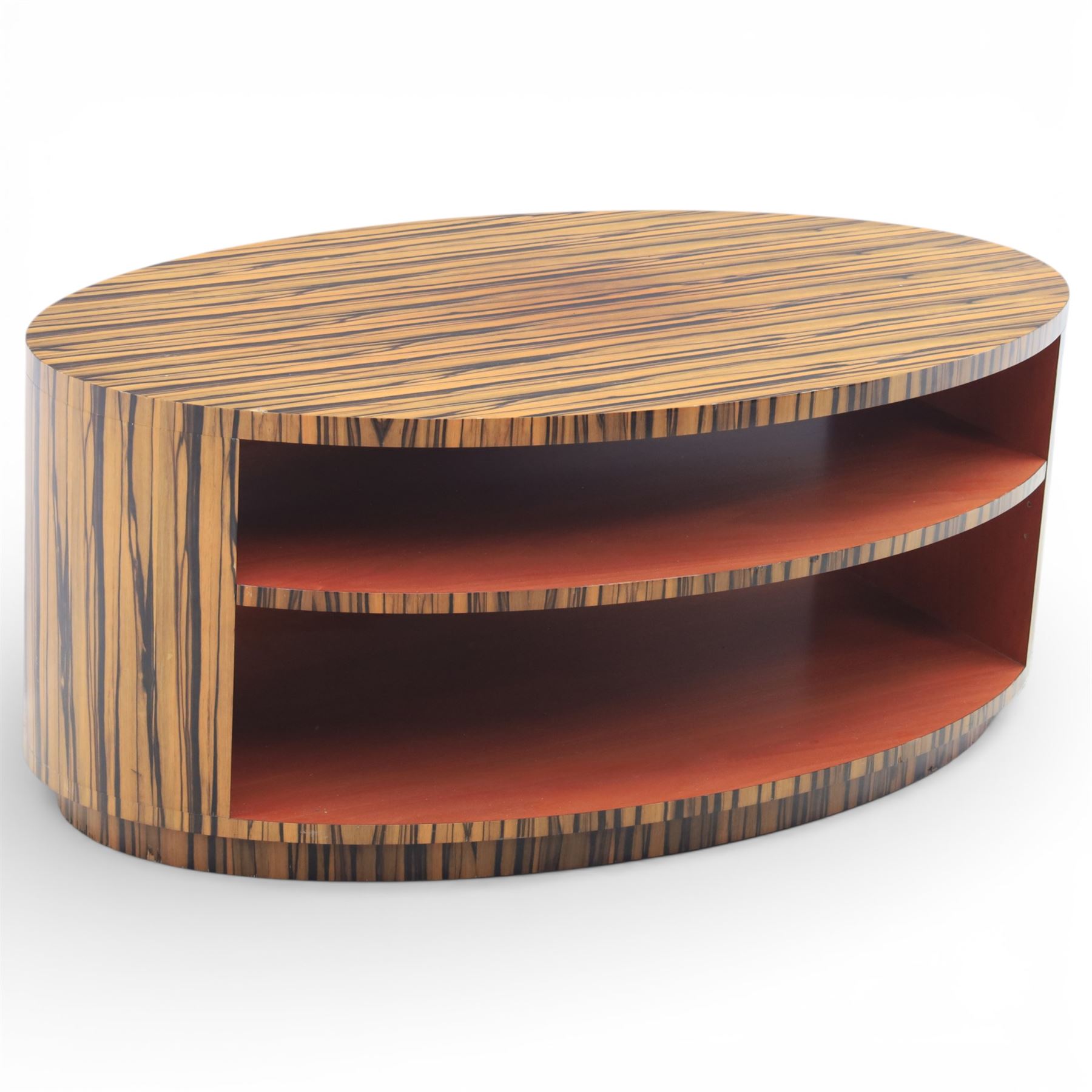 Toby Winteringham - Mid 20th century zebra wood coffee table, oval top with book matched striped veneers over two open tiers painted red, the curved end supports and continuous plinth base veneered to match, recessed plinth base 