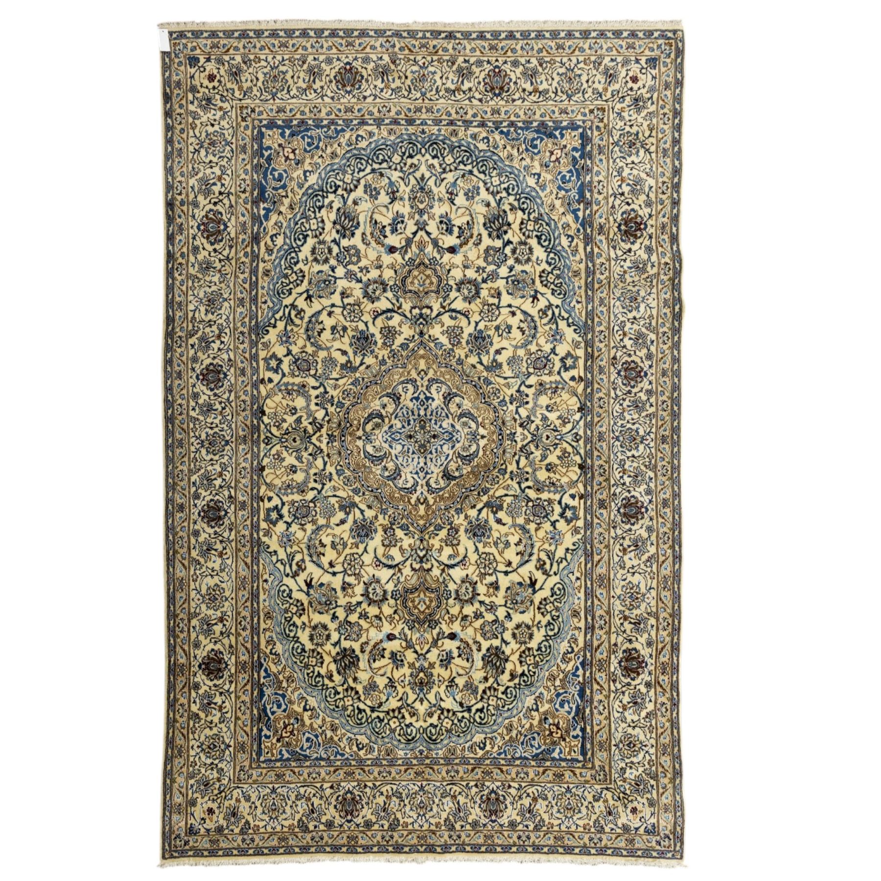 Central Persian Nain hand-knotted carpet, ivory ground, with silk highlights, centred by a shaped floral medallion with pendants, surrounded by scrolling foliate and floral motifs incorporating rosettes, palmettes and delicate vine work in blue, cream and beige tones, enclosed by blue spandrels and an ivory border with repeating palmettes and meandering vines, flanked by floral guard stripes, with cotton fringes