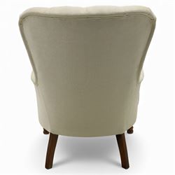 Late 20th century cream upholstered nursing chair, high button-tufted back with shaped wings, scroll arms, loose seat cushion, raised on turned front supports
