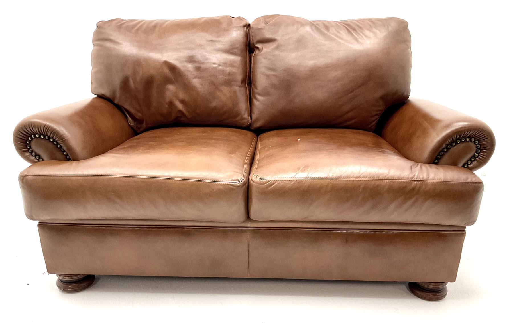 Three seat studded tan leather sofa, scrolling arms, turned supports (W190cm) with matching two seat (W155cm) armchair (W100cm) and footstool 