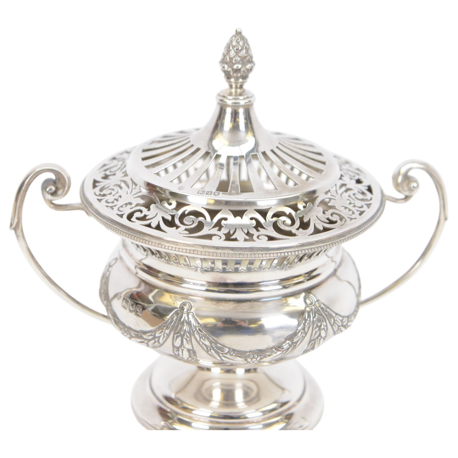 Early 20th century silver twin handled lidded bowl, of circular form with C scroll handles, the body embossed with floral swags, the pierced lid with pineapple finial, hallmarked Horace Woodward & Co Ltd, London 1911, H16cm