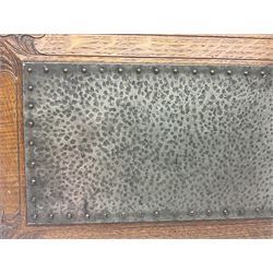 Arts and Crafts oak stand by Arthur Simpson of Kendal, of rectangular form with central hammered pewter panel, surrounded by a border with carved foliate corners, upon two bar supports, bearing label detailed 