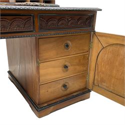 19th century Anglo-Indian teak/camphor twin pedestal desk, raised back fitted with pierced and foliate carved panelled sliding doors, enclosing pigeonholes and correspondence drawers, rectangular top with ebonised banding and moulded edge over a lunette carved frieze, fitted with nine drawers, decorated with carved and pierced mounts