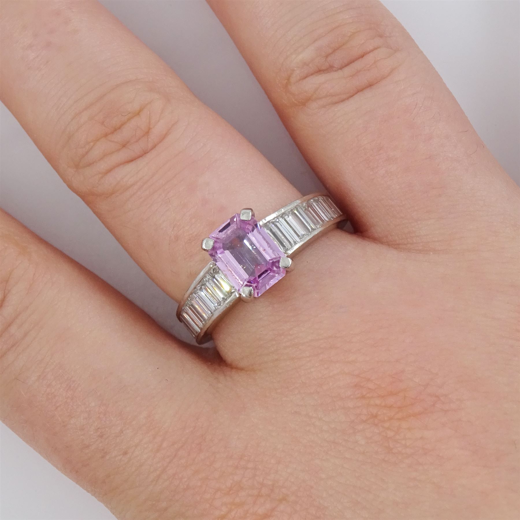 Platinum pink sapphire and diamond ring, single octagonal cut sapphire of approx 1.50 carat, each shoulder set with eleven, channel set baguette cut diamonds, London 2007, total diamond weight approx 1.05 carat