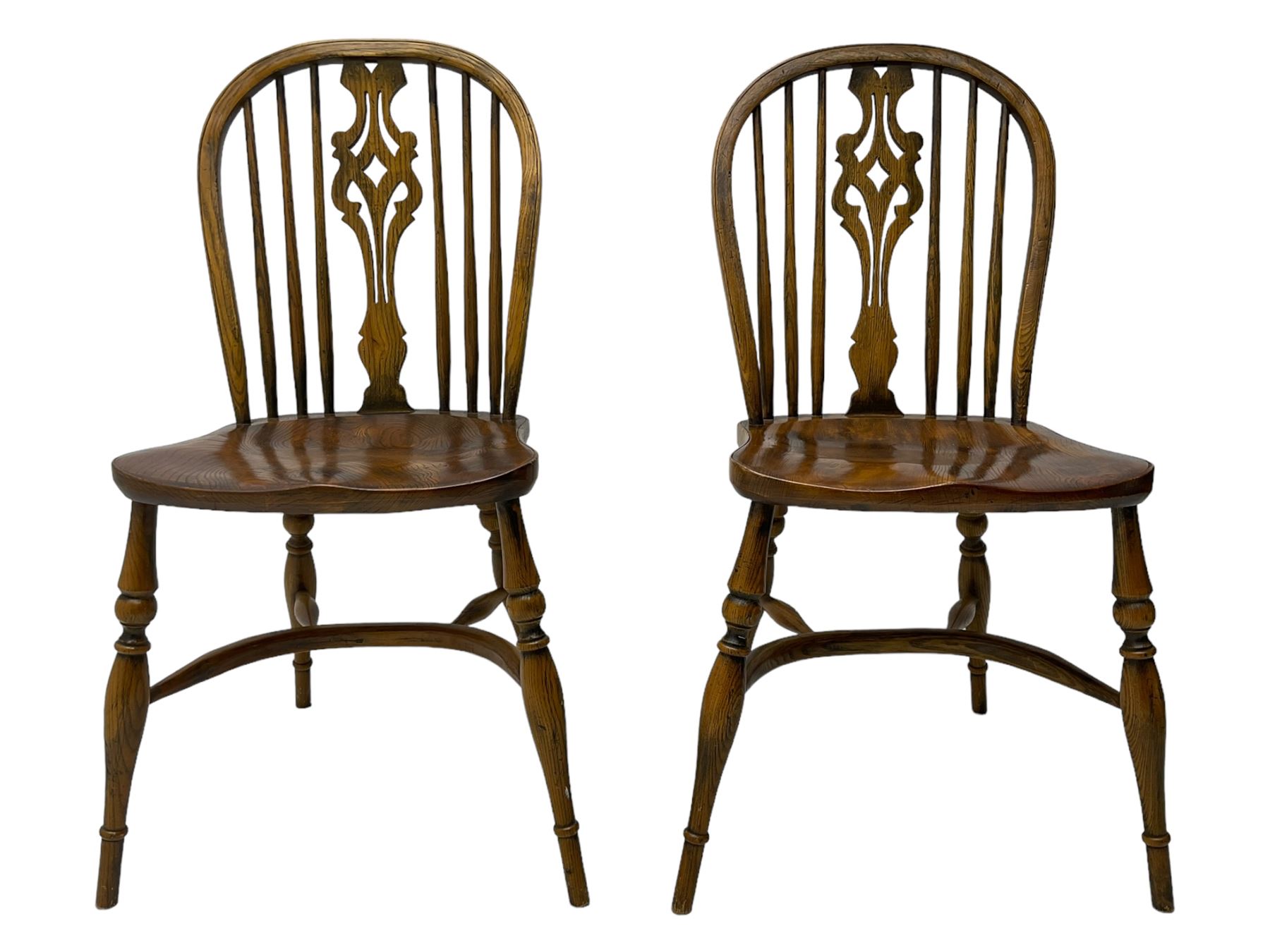Set of four elm Windsor dining chairs, high hoop and stick back with shaped pierced splat, over shaped saddle seat, raised on ring turned supports joined by crinoline stretcher