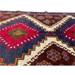 Turkish indigo ground rug, the field with two crimson geometric lozenges surrounded by flower heads with a contrasting border