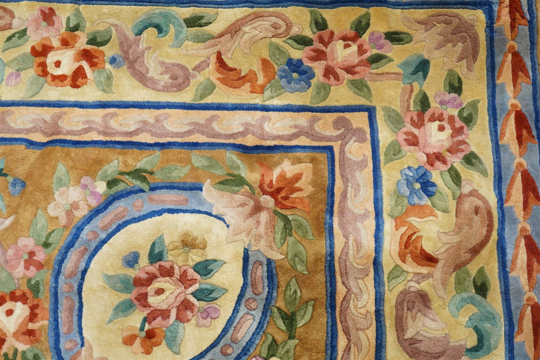 Chinese Aubusson/Savonnerie style hand-knotted carpet, ivory field with a central oval medallion issuing with stylized bouquets in shades of blush pink, pale blue, sage and green, enclosed by ribbon-tied floral garlands and conforming borders within narrow guard stripes, with cotton fringe ends 