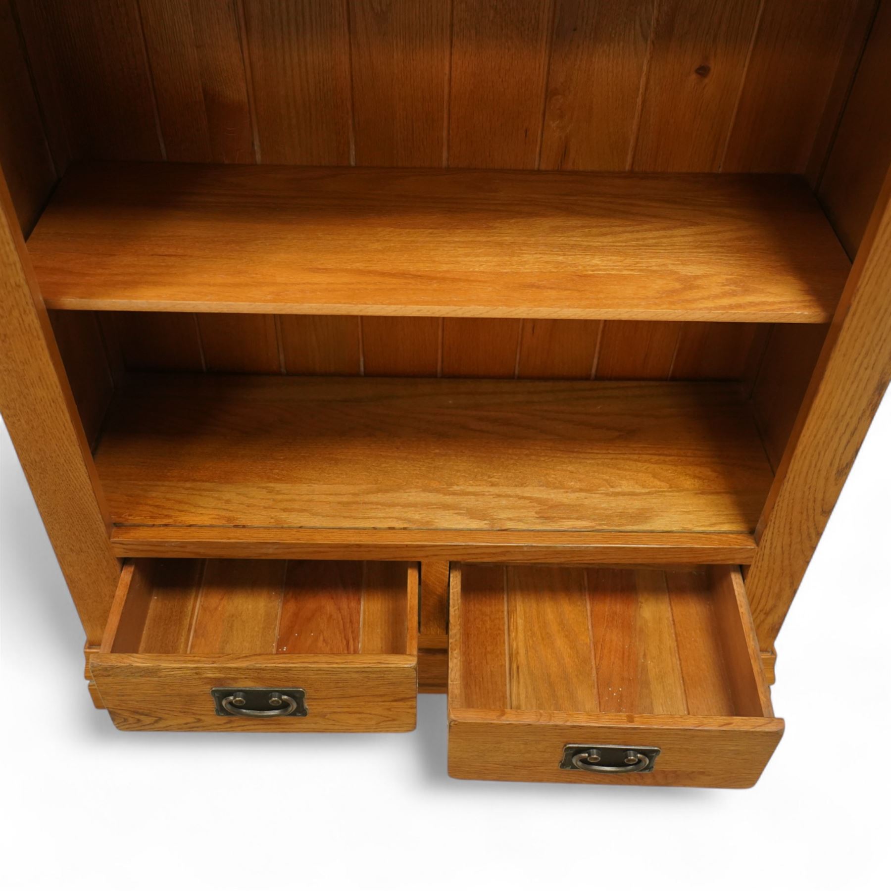 Contemporary oak bookcase, with moulded cornice above open shelved interior, fitted with four adjustable shelves and two short drawers with inset brass handles, panelled sides, plinth base